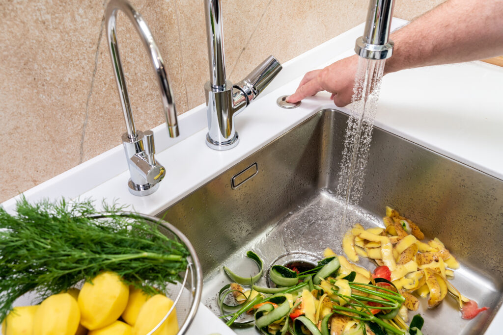 Turning on a disposer in a modern kitchen to remove food waste.