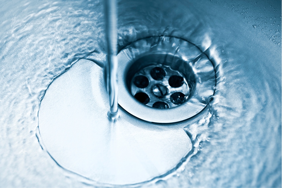 A plumber clearing clogged pipes under a kitchen sink