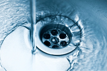 A plumber clearing clogged pipes under a kitchen sink